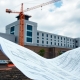 Prison construction site with crane and blueprints.