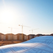 Construction site with cranes, houses, and a blueprint.