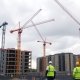 Croydon housing site with cranes and workers resuming construction.