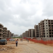 Construction site with few workers and unfinished buildings.